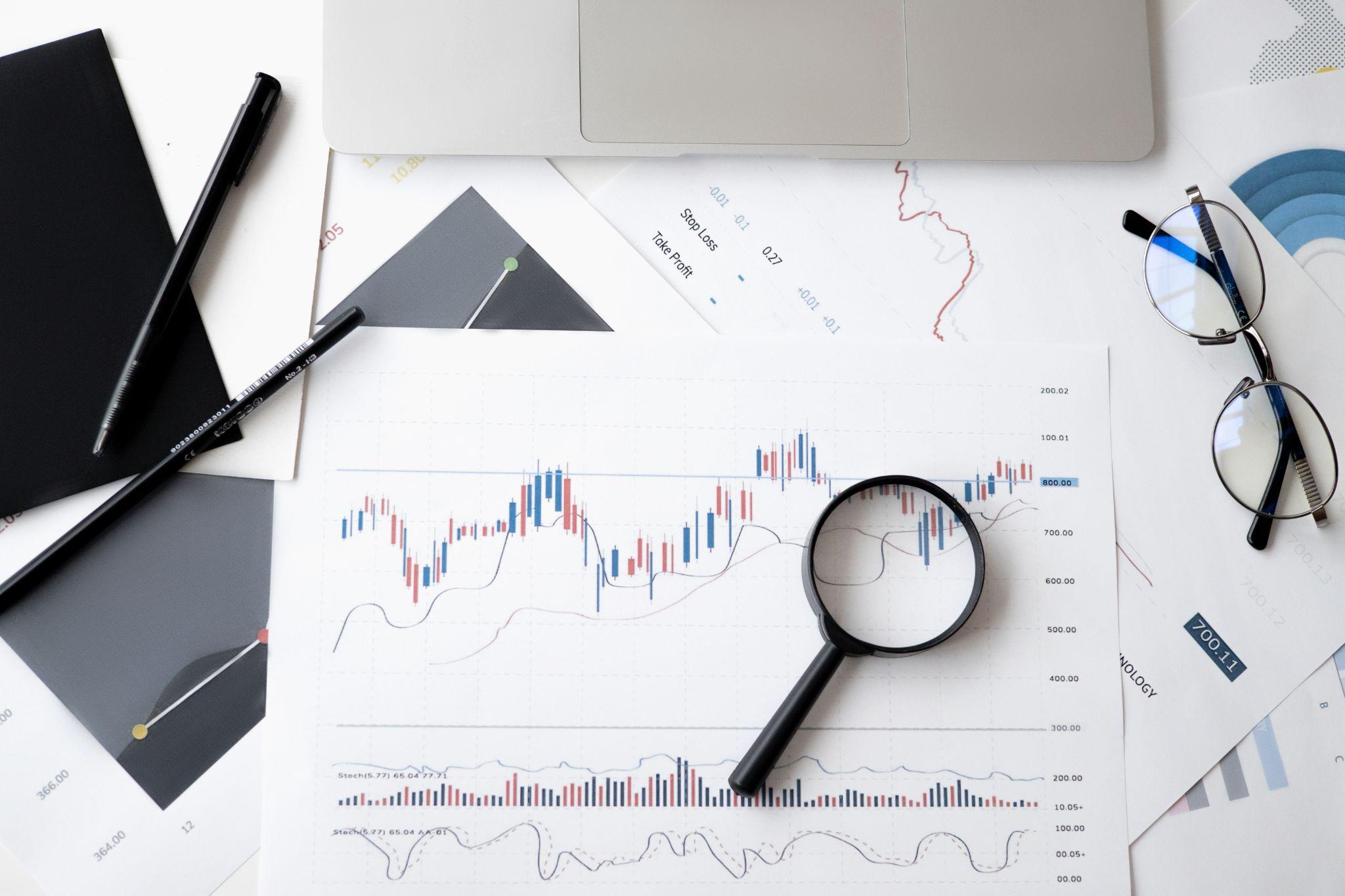 papers with charts, glasses and a magnifying glass