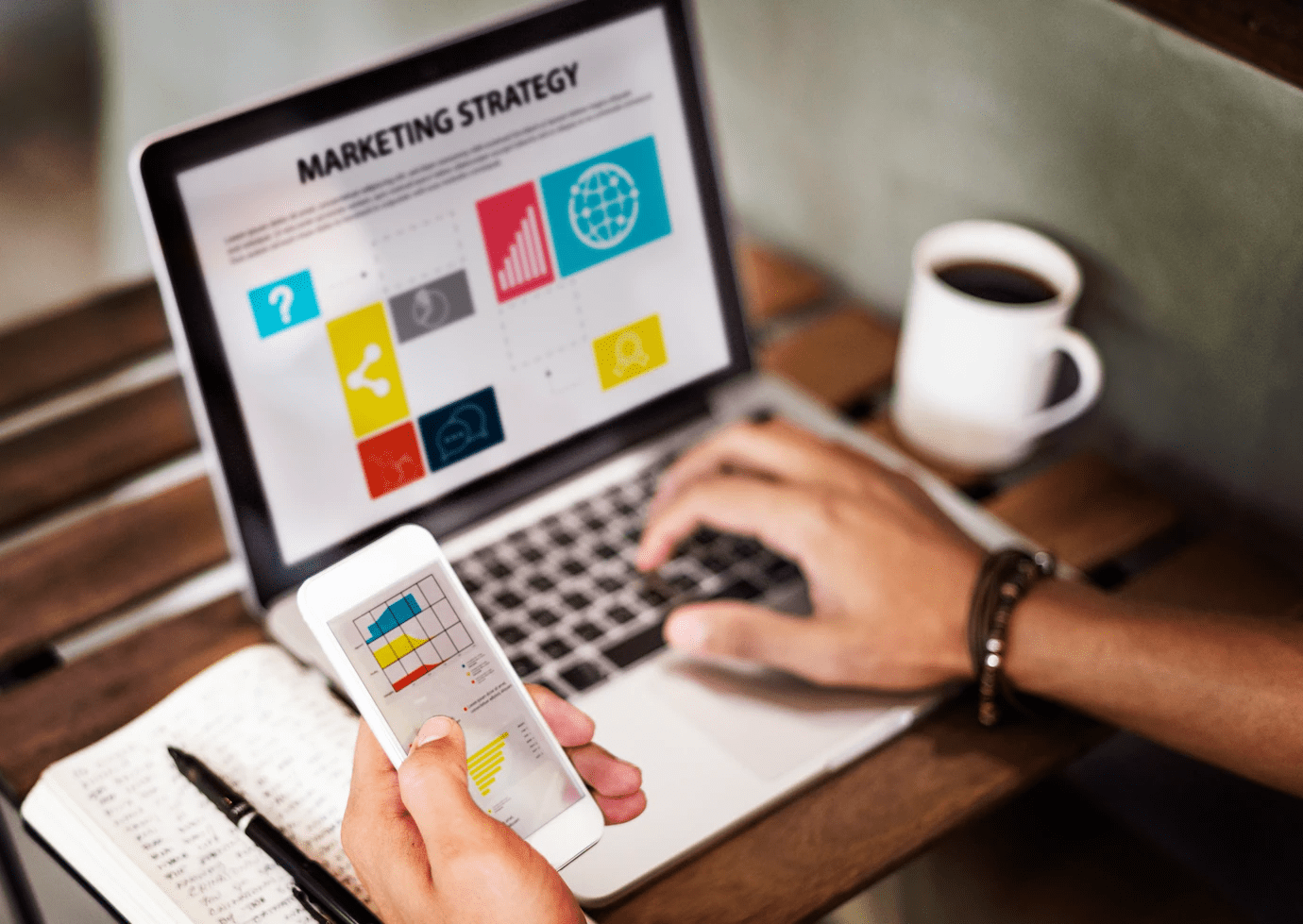 person using a laptop and a mobile phone to look at marketing strategy