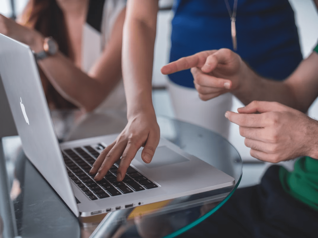 people discussing and pointing at a laptop