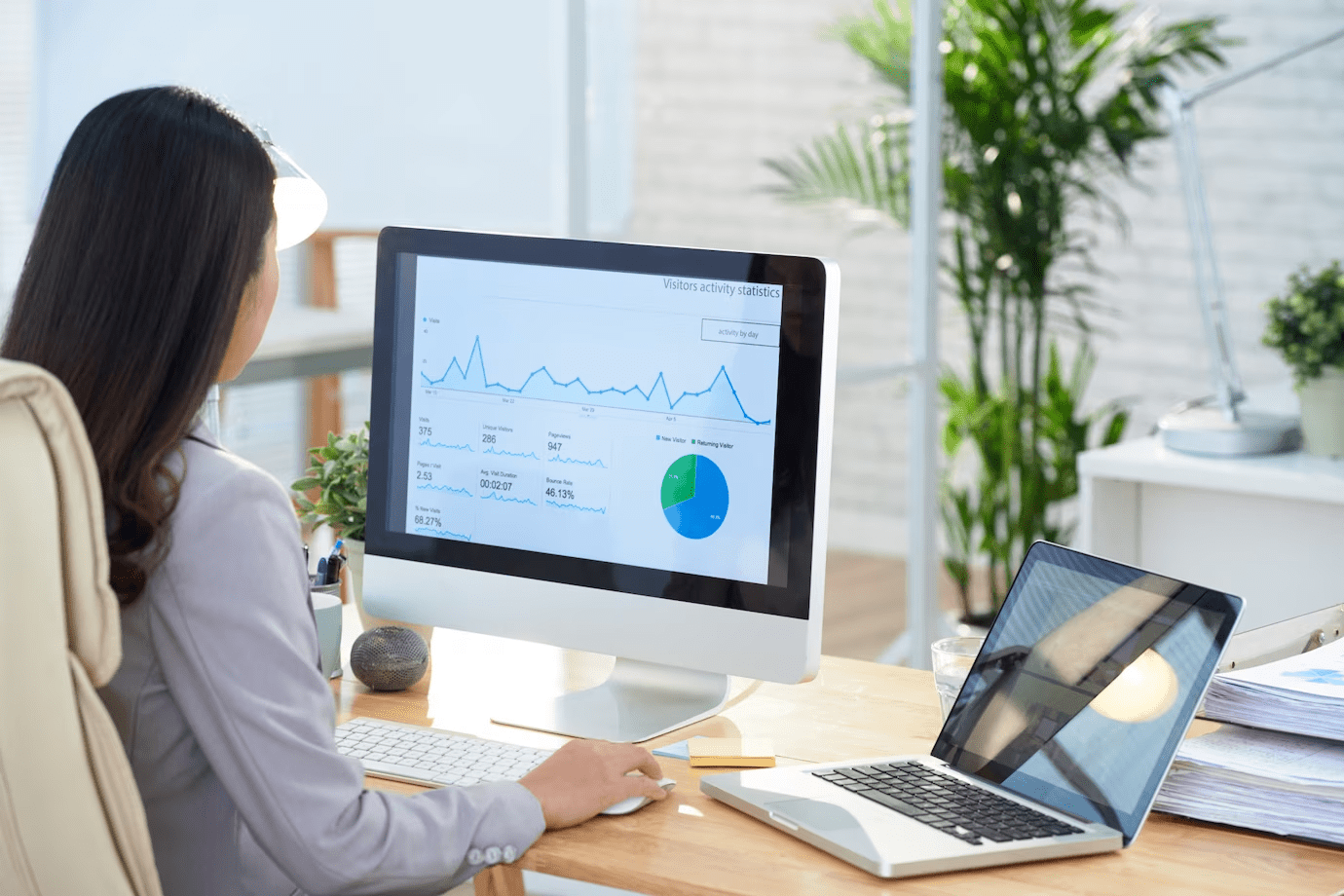 woman looking at charts on a computer and a laptop