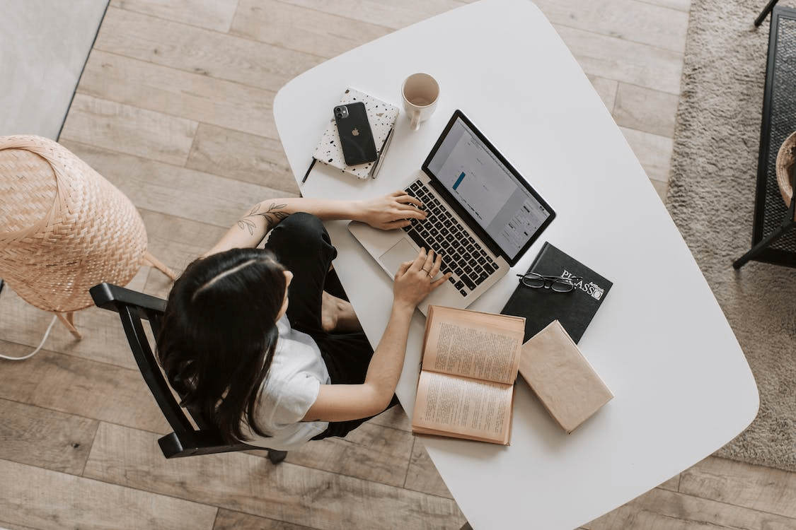 woman sitting at a table and typing on a laptop