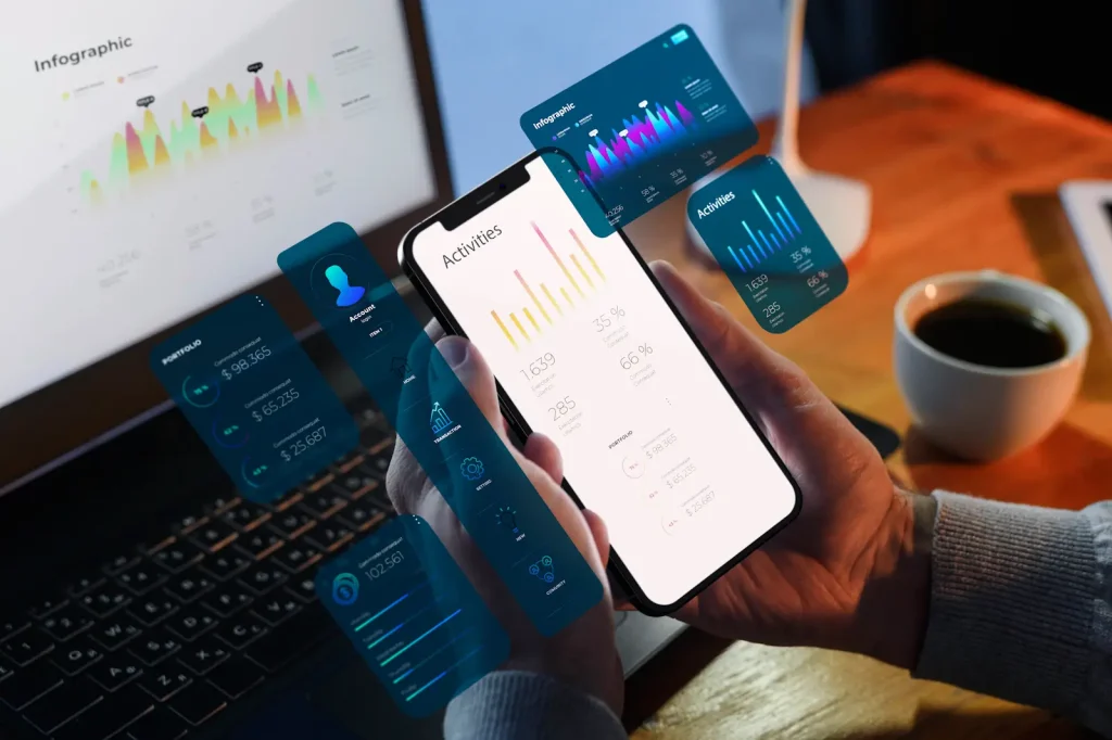 Illustration showing a person holding a smartphone with analytics dashboards overlaid on the screen, alongside a laptop displaying charts and graphs under the heading “Mobile Analytics vs. Web Analytics.”