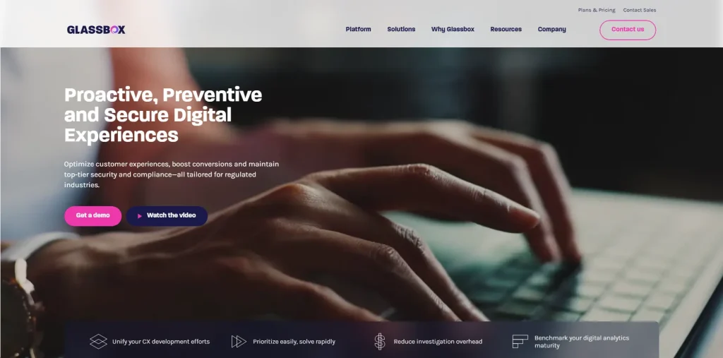 Glassbox homepage hero banner promoting proactive, preventive, and secure digital experiences with a close-up background image of hands typing on a keyboard and demo CTA buttons.
